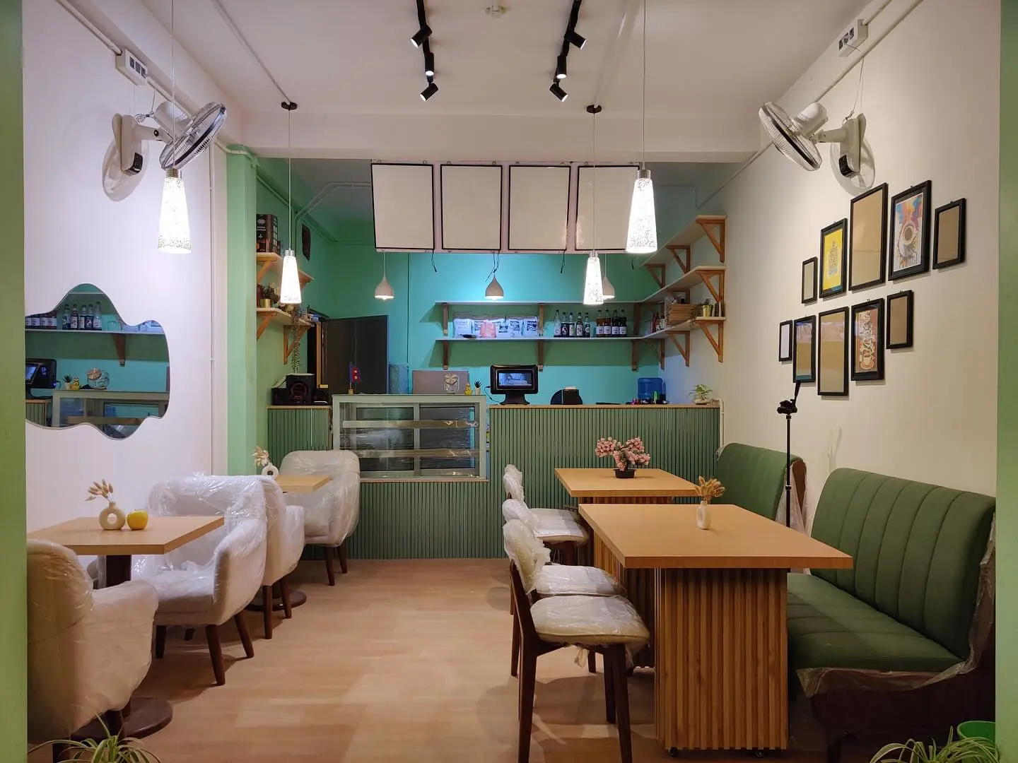 Inside Noko: the counter, green booths and a wall of framed prints under warm pendant lights